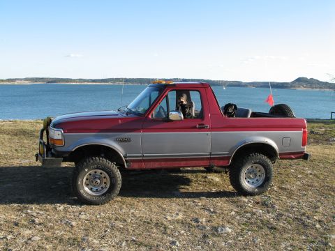1995 Ford Bronco - Side view of a two-tone red and silver 1995 Ford Bronco with dogs enjoying the scenery.