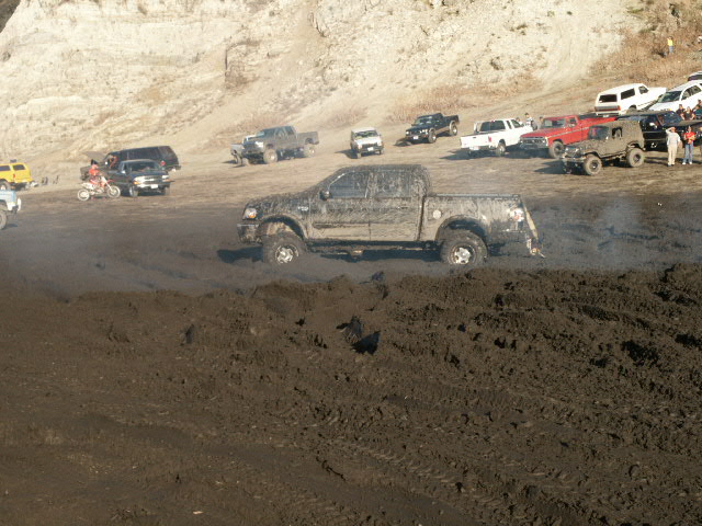Mud-covered Ford F-150 pickup truck stuck in mud, side view