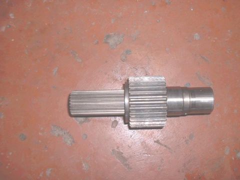 1995 Ford Bronco - A metal shaft with splines on one end and a gear on the other is shown against a reddish-brown background.