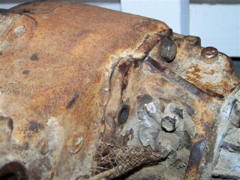 1995 Ford Bronco - A close-up view of a corroded metal component, likely an engine part, showing significant rust and wear.