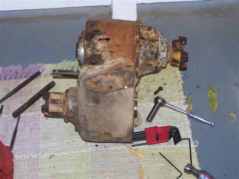 1995 Ford Bronco - A heavily rusted transmission or transfer case sits on a rug with various tools nearby.