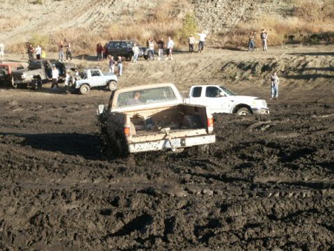 1978 Ford Bronco - Multiple vehicles are stuck in thick mud during an off-road event.