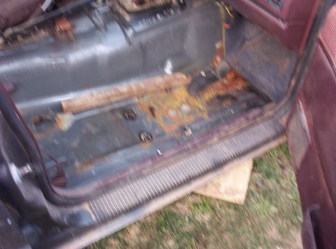 1987 Jeep Cherokee - The interior floor of a vehicle shows extensive rust and damage, indicating a need for repair.