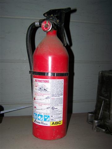 1995 Ford Bronco - A red fire extinguisher with instructions and a pressure gauge is visible, along with some unidentifiable vehicle parts in the background.