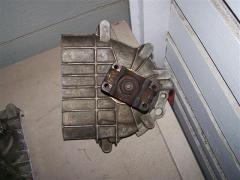 1995 Ford Bronco - A metal transmission part is shown, with visible casting numbers and mounting points.