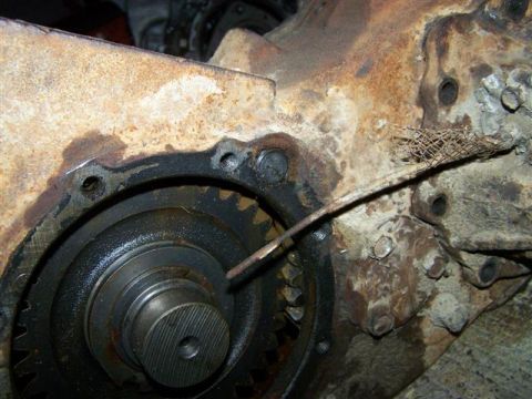 1995 Ford Bronco - A close-up view of a corroded mechanical part, showing gears and a damaged wire mesh.