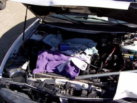 1993 Ford Probe - The engine bay of a car is shown with the hood up, partially covered by towels and various parts.