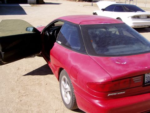 1993 Ford Probe - Red 1993 Ford Probe with driver door open, parked on dirt with another car behind it.