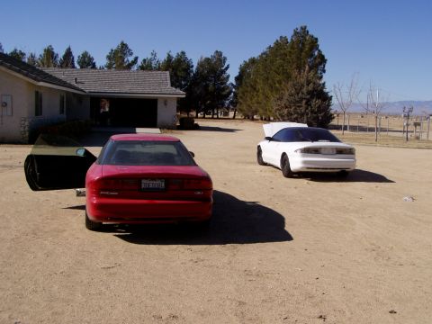 1993 Ford Probe - Two Ford Probes are parked outside a house on a sunny day, with one showing its engine bay.