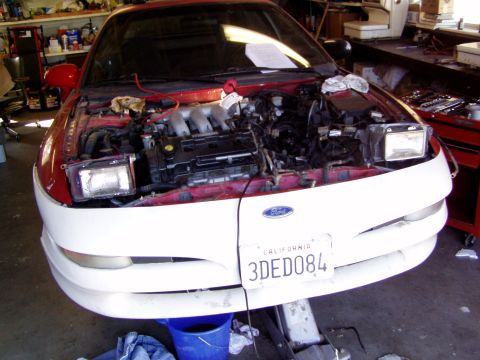 1993 Ford Probe - The engine bay of a 1993 Ford Probe is exposed for maintenance, with the front bumper also visible.