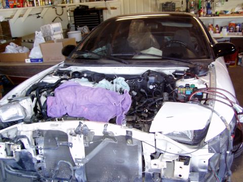 1993 Ford Probe - The front of a white 1993 Ford Probe is shown with its hood open and engine bay exposed, indicating ongoing work.