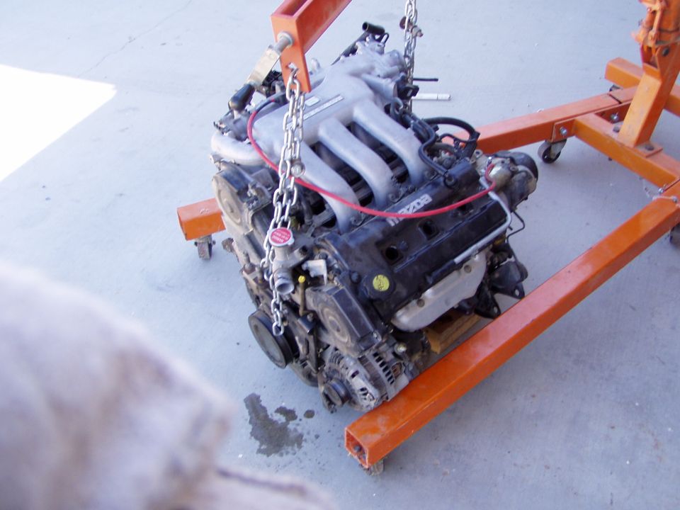 Mazda engine being held by an orange engine stand, chains attached