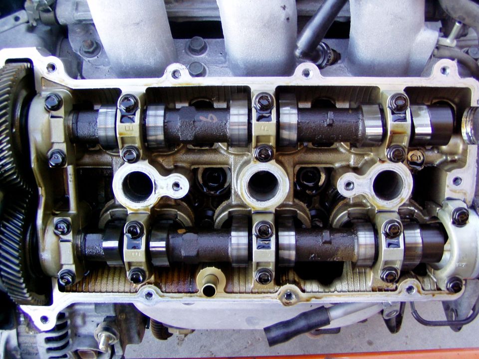 DOHC cylinder head with valve cover removed showing dual camshafts and cam gear