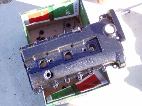 1993 Ford Probe - A silver engine valve cover with the 'MAZDA' logo is shown resting in a cardboard box, possibly during a swap or repair.