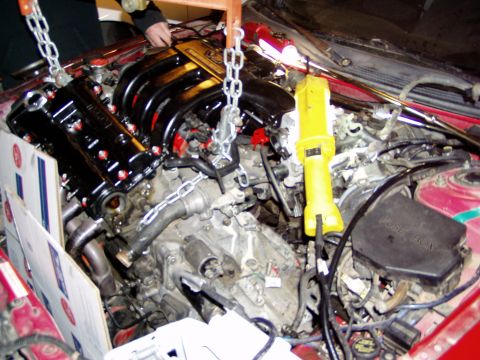 1993 Ford Probe - Engine bay work in progress, with chains and a yellow work light.
