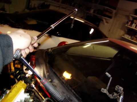 1993 Ford Probe - Mechanic works on a car's engine bay, with another vehicle in the background.