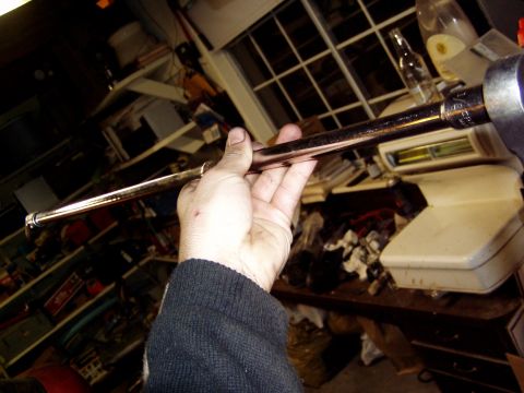 1993 Ford Probe - A hand holds a metal rod with a socket, likely part of a tool set, in a cluttered garage setting.