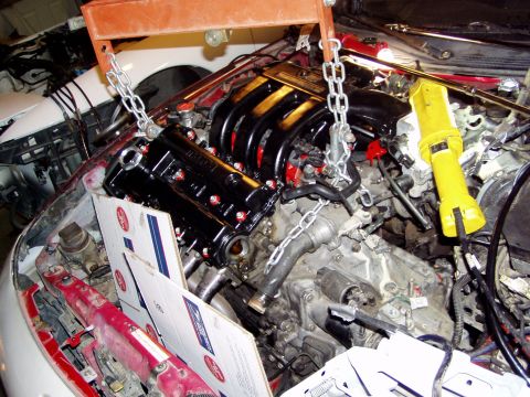 1993 Ford Probe - Engine hoist supporting engine components during work in a car's engine bay.