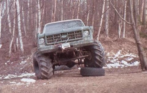 1982 Chevrolet C/K Pickup - A modified Chevrolet pickup truck with oversized tires and a winch is shown in a forest setting.