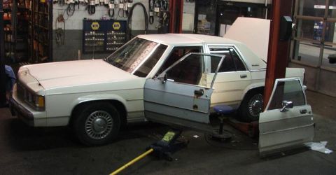 1991 Ford Crown Victoria LTD - White 1991 Ford Crown Victoria LTD undergoing repairs in a workshop, with its doors detached.
