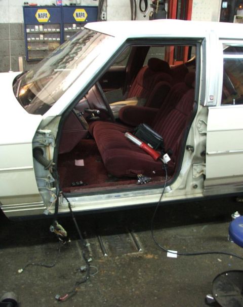 1991 Ford Crown Victoria LTD - The interior of a sedan is shown with the driver's side door removed, revealing exposed wiring and maroon upholstery.