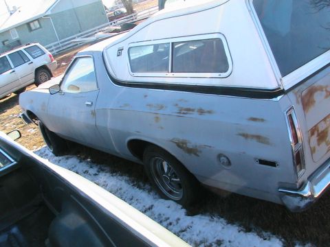 1973 Ford Ranchero - A 1973 Ford Ranchero pickup truck is parked outside with a camper shell on the bed.