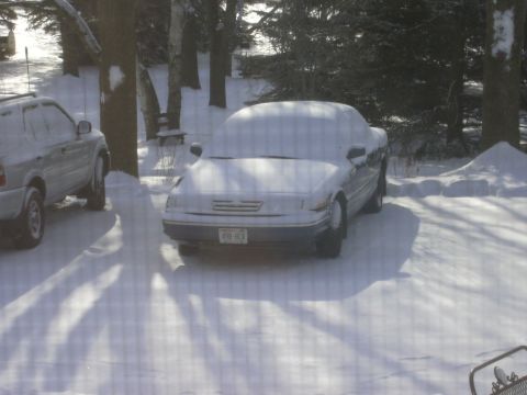 1996 Ford Crown Victoria - Two vehicles, a 1996 Ford Crown Victoria and an SUV, are parked outside and covered in snow.