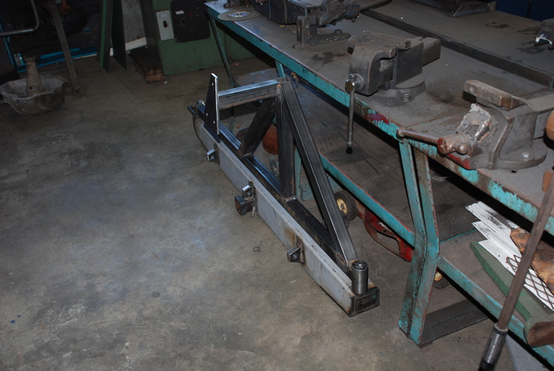 Metal fabrication for a custom rear bumper, showing welded steel beams and mounting brackets on a workbench