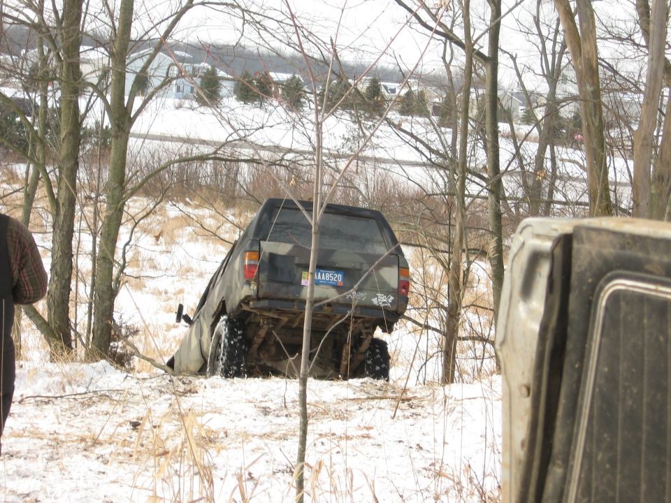 Dark SUV tilted in snow, rear view, license plate visible