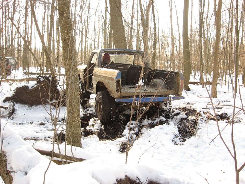 Modified off-road truck stuck in mud and snow, another SUV visible in background