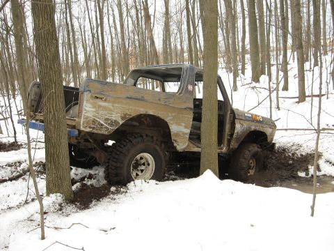 1979 Ford Bronco - This 1979 Ford Bronco is stuck in the mud and snow, surrounded by trees in a wooded area.