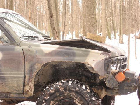 1979 Ford Bronco - SUV with significant front-end damage sits in a snowy wooded area.