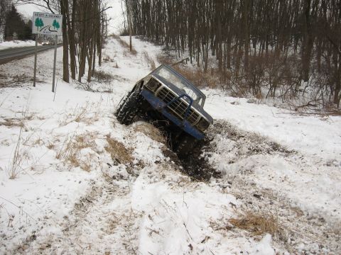 1979 Ford Bronco - A blue 1979 Ford Bronco is stuck in a snowy ditch off a rural road.