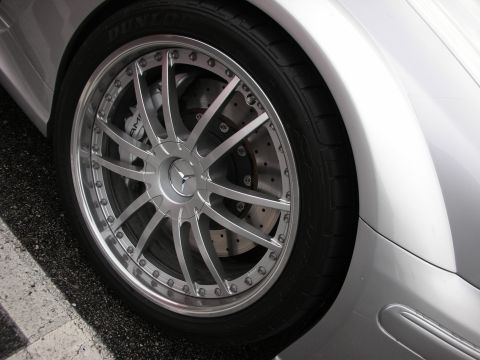 1998 Ford Crown Victoria - Close-up of a polished multi-spoke wheel on a silver Mercedes, Dunlop tire and drilled brake rotor with center logo.