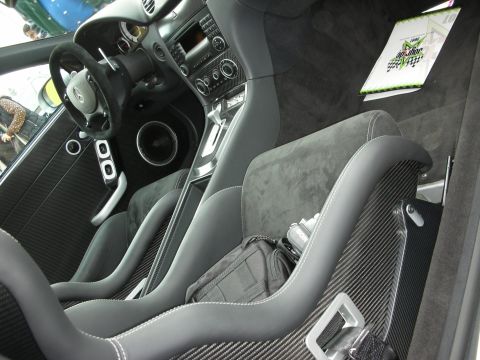 1998 Ford Crown Victoria - Interior of a high-end sports car showing carbon-fiber bucket seats, suede upholstery, and a center console at an indoor display.