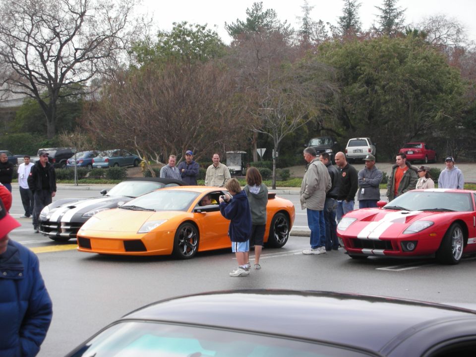 Orange Lamborghini, red Ford GT and striped car at an outdoor car gathering