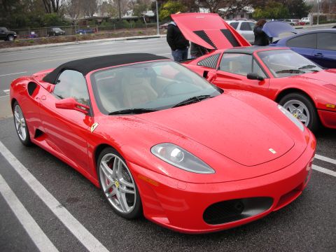 1998 Ford Crown Victoria - Red Ferrari F430 Spider with top up, shown front three-quarter, parked beside other Ferraris on a marked lot.