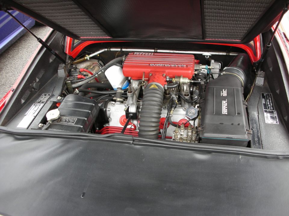 Open engine bay of a Ferrari showing a red Quattrovalvole V engine