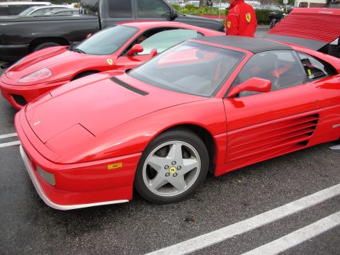 1998 Ford Crown Victoria - Red Ferrari 348 with five-spoke wheels in the foreground and a second red Ferrari behind, parked on a marked lot.