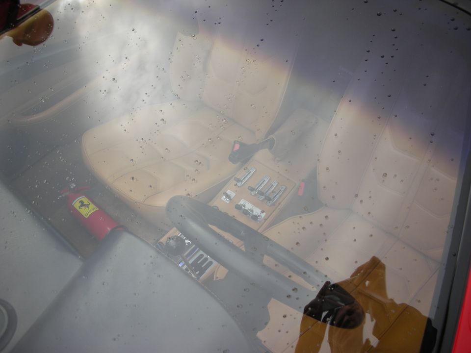 Tan leather Ferrari interior seen through a rain-dotted window