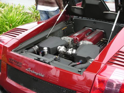 1998 Ford Crown Victoria - Engine bay of a dark red Lamborghini Gallardo fitted with a Heffner twin-turbo system, deck lid raised.