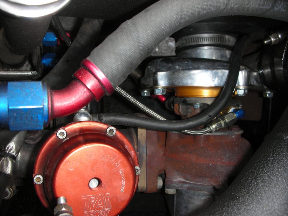 Turbocharger plumbing with red and blue AN fittings and an orange wastegate