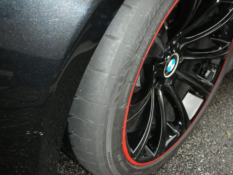 Close-up of a black BMW wheel with red rim pinstripe and low-profile tire