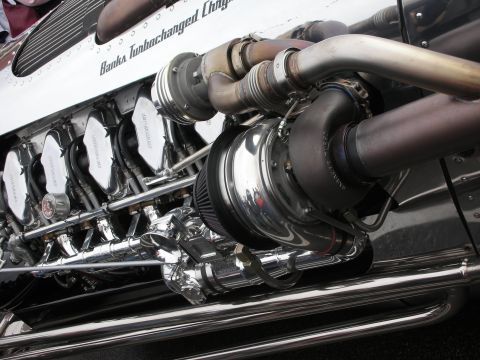 1998 Ford Crown Victoria - Detailed close-up of a polished Banks turbocharged Chrysler V12 engine showing chrome turbo, headers, and intake runners.
