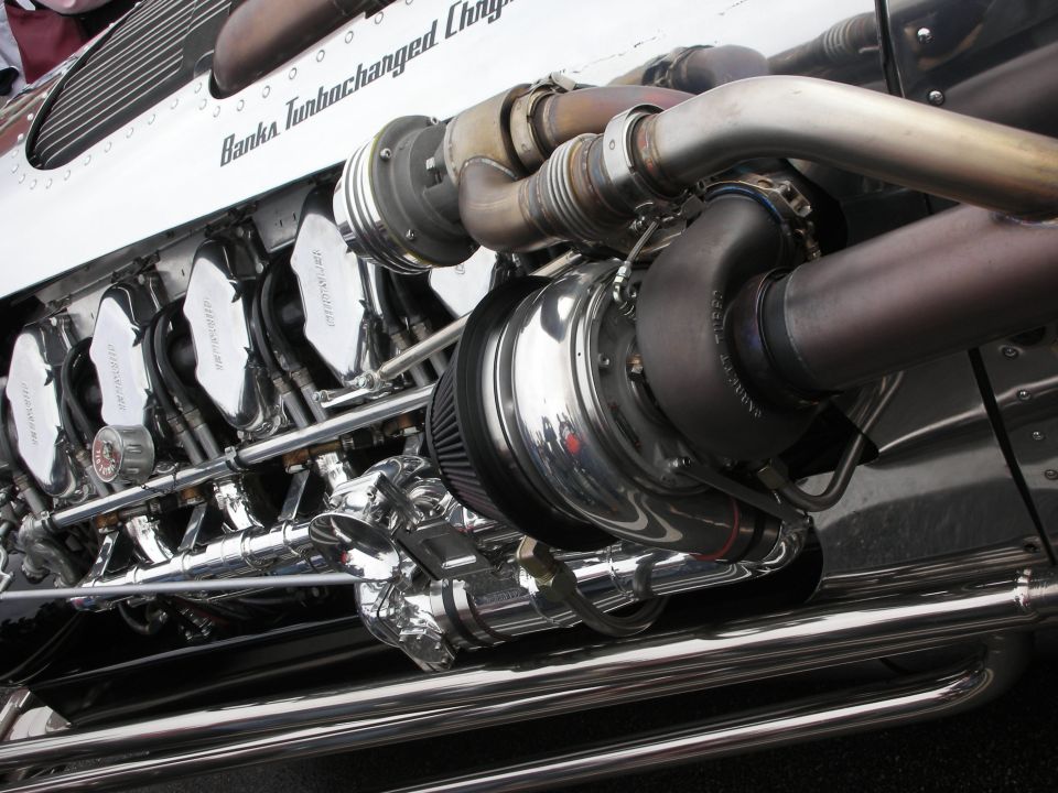 Close-up of a polished chrome V12 engine with turbocharger and headers