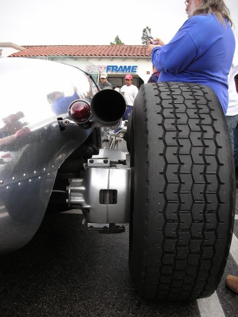 1998 Ford Crown Victoria - Rear quarter of a polished silver hot rod showing a large round exhaust outlet next to a chunky dual rear tire.
