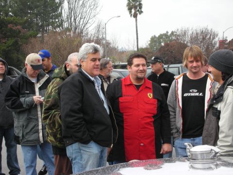 1998 Ford Crown Victoria - Several men in jackets stand and chat outdoors by a car, one wearing a red Ferrari-logo shirt.