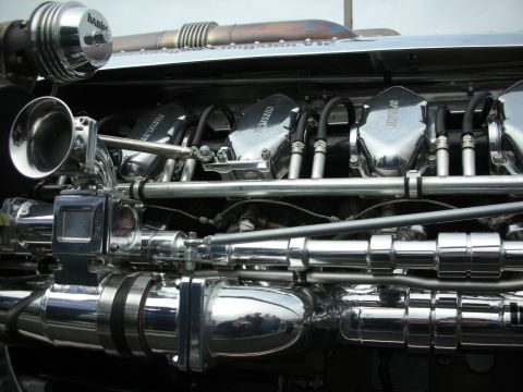 1998 Ford Crown Victoria - highly polished chrome engine showing valve covers, velocity stacks, and intricate plumbing.