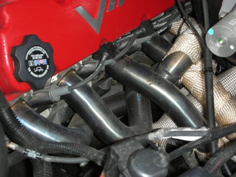 1998 Ford Crown Victoria - Dark tubular exhaust headers and heat-wrapped piping next to a red VIPER-marked valve cover.