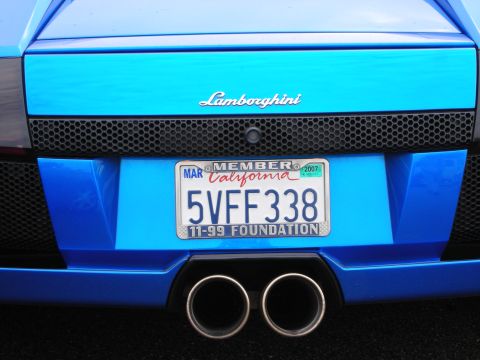 1998 Ford Crown Victoria - Close-up of a blue Lamborghini's rear showing the badge, a California plate, and dual exhaust tips.